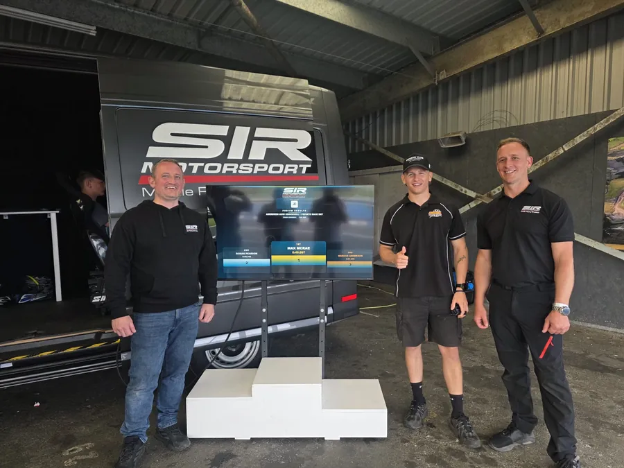 SIR Motorsport team beside a live race-day podium leaderboard