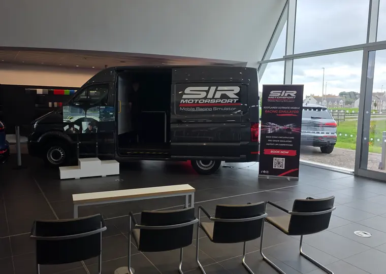 SIR Motorsport simulator van set up inside a premium automotive showroom with display boards and performance cars.