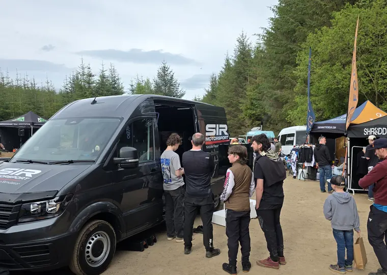 SIR Motorsport mobile simulator van with guests gathered at an outdoor motorsport event.