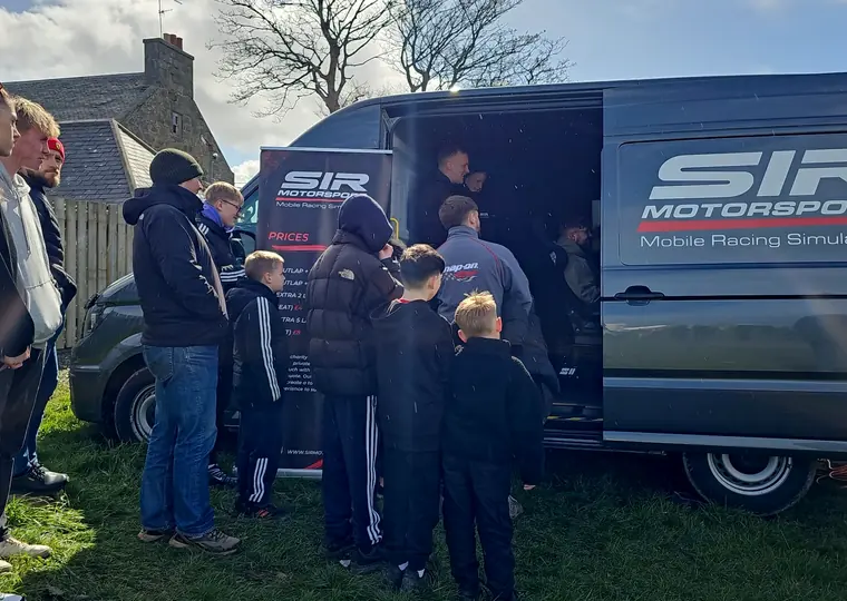 Guests gathered beside the SIR Motorsport simulator van during a public event.