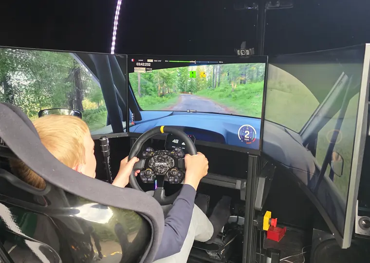 Over-shoulder view of a driver racing on the simulator during an event.
